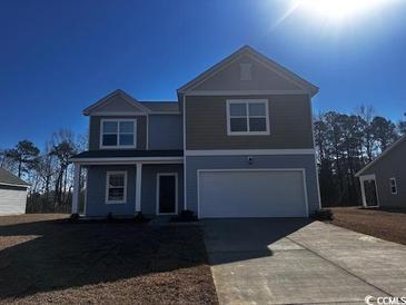 Charming two-story home featuring light blue siding, a two-car garage, and a well-manicured lawn at 660 Castillo Dr., Loris, SC 29569