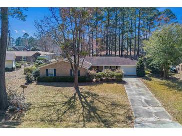 Charming brick home featuring a well-maintained lawn, mature trees, and a paved driveway leading to an attached garage at 1917 Candy Ln., Surfside Beach, SC 29575