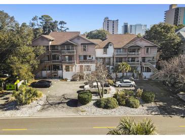 This is an exterior shot of a condominium with a parking lot and well-kept landscaping near the building at 306 74Th Ave. N # 105, Myrtle Beach, SC 29572