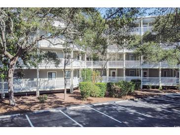 Multi-story condo building with white balconies, surrounded by trees and a parking lot at 415 Ocean Creek Blvd. # 2333, Myrtle Beach, SC 29572