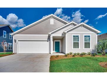 Charming single-Gathering home featuring a 1-car garage, teal front door, and beautifully landscaped front yard at 453 Kapalua Loop, Little River, SC 29566