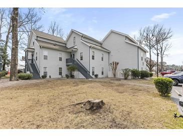 Exterior view of a two-story residential building with gray siding and stairs leading to the upper units at 4350 Spa Dr. # 506, Little River, SC 29566