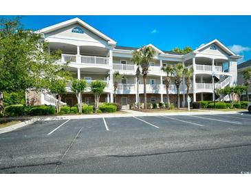 Attractive condo building with multiple balconies and mature landscaping near parking lot at 5801 Oyster Catcher Dr. # 723, North Myrtle Beach, SC 29582
