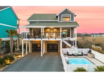 Stunning elevated coastal home featuring a private pool, black garage doors, and dual balconies at 604 Ocean Boulevard W, Holden Beach, NC 28462