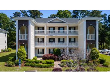 Three-story condo building with white siding, black shutters, and well-manicured landscaping at 1220 River Oak Dr. # 22C, Myrtle Beach, SC 29579