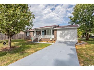 Charming brick home featuring a front porch, metal roof, and well-maintained landscaping at 1819 Martin Circle, Myrtle Beach, SC 29579