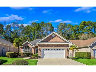 Charming brick home with a well-manicured lawn, lush landscaping, and a two-car garage at 3079 Alice Ln., Little River, SC 29566