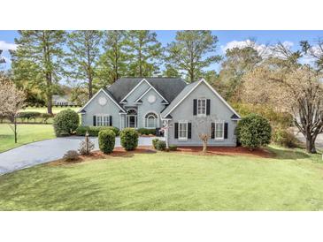Charming single-story home featuring a manicured lawn, mature trees, and elegant architectural details at 75 Haig Ct., Georgetown, SC 29440