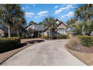 Charming brick home with a circular driveway, lush landscaping, and mature palm trees at 9800 Plumfield Ct., Myrtle Beach, SC 29579