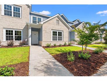 Charming townhome with light brick, blue siding, manicured lawn, and inviting walkway leading to the front door at 344 Kiskadee Loop # E, Conway, SC 29526