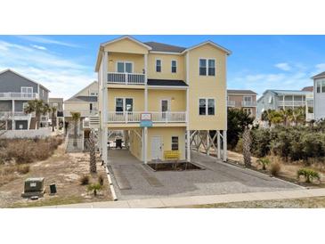 Inviting three-story yellow beach home with dual balconies and stylish coastal design at 436 E Third St., Ocean Isle Beach, NC 28469