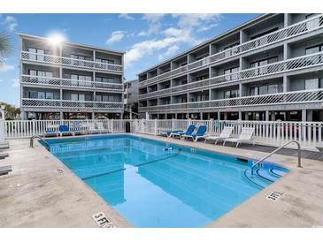 Inviting community pool with lounge chairs, surrounded by well-maintained condo buildings under a sunny sky at 627 North Waccamaw Dr. # 212, Murrells Inlet, SC 29576