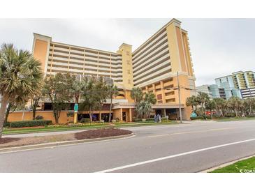 Spacious condo building with yellow facade, parking garage and view of the street at 6900 N Ocean Blvd. # 1008, Myrtle Beach, SC 29572