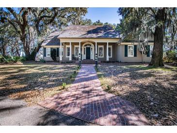 Inviting traditional home with a brick walkway, lovely lawn, and stately trees draped with Spanish moss at 762 Wraggs Ferry Rd., Georgetown, SC 29440