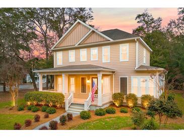 Charming two-story home boasts a welcoming front porch and manicured landscaping, complete with the American flag at 9100 Sw Fountain St., Calabash, NC 28467