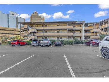 Condo building exterior with parking lot, featuring multiple balconies and neutral tones at 9501 Shore Dr. # D-132, Myrtle Beach, SC 29572
