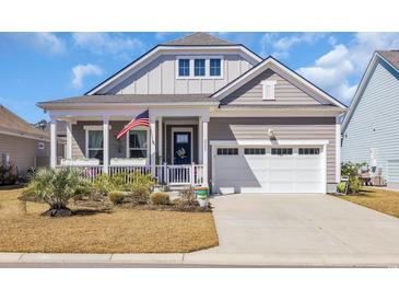 Charming home featuring a covered porch with American flag, and an attached garage with white door at 2005 Silver Island Way, Murrells Inlet, SC 29576