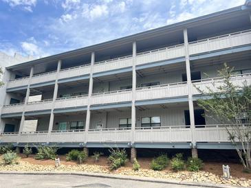 Multi-level condo building featuring private balconies and a well-maintained landscaped yard on a sunny day at 310 5Th Ave. N # 206, Surfside Beach, SC 29575