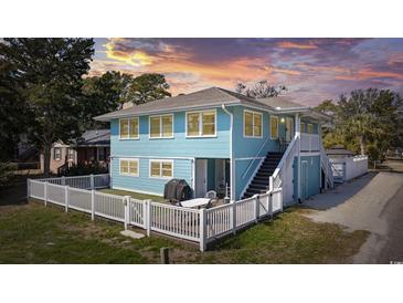 Charming two-story blue house with a white picket fence and outdoor patio area at sunset at 401 25Th Ave. S, North Myrtle Beach, SC 29582