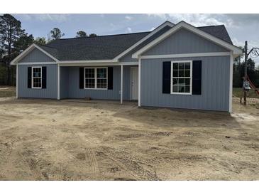 Charming one-story home with gray siding, black shutters, and a dark roof at 813 Highway 67, Loris, SC 29569