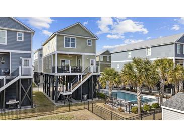 Charming elevated beach house with private pool, lush landscaping, and black wrought iron fence at 132 Garden City Retreat Dr., Murrells Inlet, SC 29576