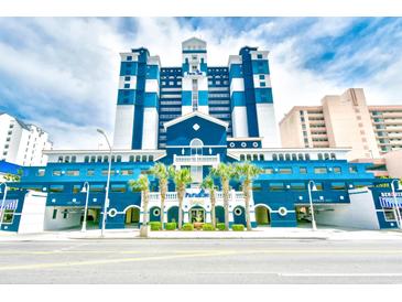 Modern building exterior featuring blue and white accents, lush palm trees, and an inviting entrance at 2201 S Ocean Blvd. # 2010-2011, Myrtle Beach, SC 29577