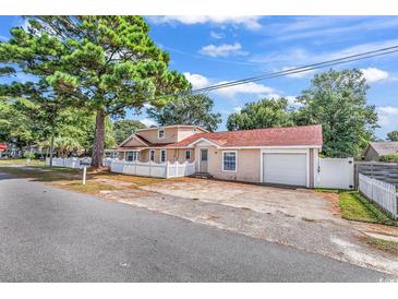 Charming home with a large tree, white picket fence, and a detached garage at 111 S Poplar Dr., Surfside Beach, SC 29575