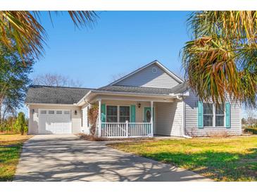 Charming single-story home with a well-manicured lawn, attached garage, and covered front porch at 125 Dayglow Dr., Loris, SC 29569