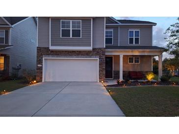 Two-story home with stone accents, a two-car garage, professional landscaping, and a cozy, covered front porch at 1330 Reflection Pond Dr., Little River, SC 29566