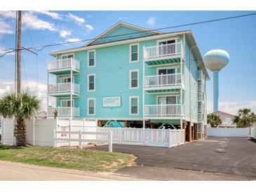 Turquoise condo with three stories, white railings, palm tree, and asphalt drive on a clear day with a blue sky at 212 58Th Ave. N # 1C, North Myrtle Beach, SC 29582