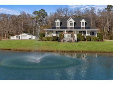 Charming two-story home with a sprawling lawn, beautiful pond with fountain, and white picket fence at 2325 Highway 111, Little River, SC 29566