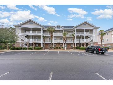 Three-story condo building with white balconies, a parking lot and some landscaping at 5801 Oyster Catcher Dr. # 724, North Myrtle Beach, SC 29582
