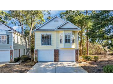 Charming two-story home with a two-car garage and light yellow siding surrounded by mature trees at 670 2Nd Ave. N, North Myrtle Beach, SC 29582
