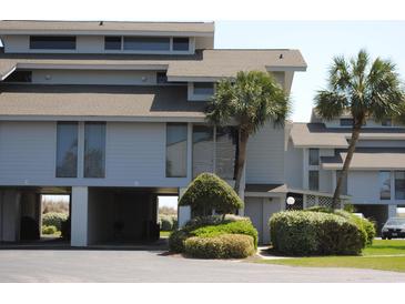 Coastal home exterior featuring covered parking, palm trees, and tidy landscaping at 671 Norris Dr., Pawleys Island, SC 29585