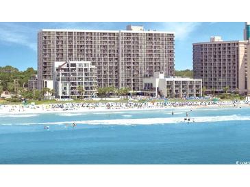 Expansive beachfront view of a tall condo building overlooking beach with many residents enjoying the ocean and sand at 7200 N Ocean Blvd. # 136, Myrtle Beach, SC 29572
