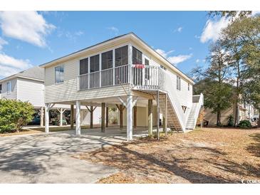 Charming raised beach house with a screened porch, sturdy stilts, and lush, low-maintenance landscaping at 939 Tiffany Ln., North Myrtle Beach, SC 29582