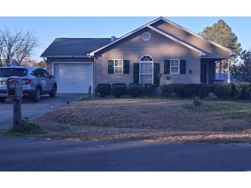 Charming single-story home featuring a well-manicured lawn, attached garage, and inviting front porch at 9903 Conifer Ln., Murrells Inlet, SC 29576