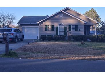 Charming single-story home with a manicured lawn, attached garage, and welcoming curb appeal at 9903 Conifer Ln., Murrells Inlet, SC 29576