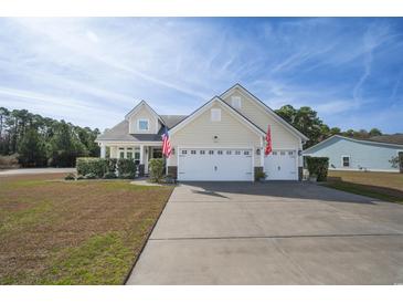 Inviting home featuring a three-car garage, well-manicured landscaping, and charming American flag at 1201 Ficus Dr., Myrtle Beach, SC 29579