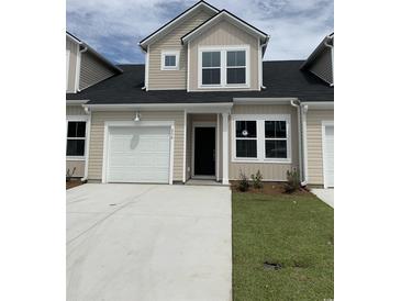 Charming tan two-story townhome featuring a garage, black front door, and a manicured lawn at 160 Hoffman Park Dr. # 13, Myrtle Beach, SC 29588