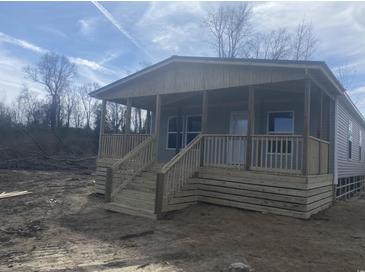 A charming, newly built single story home featuring a covered porch with wooden railing and stairs, enhancing its curb appeal at 491 N Green Sea Rd., Loris, SC 29569