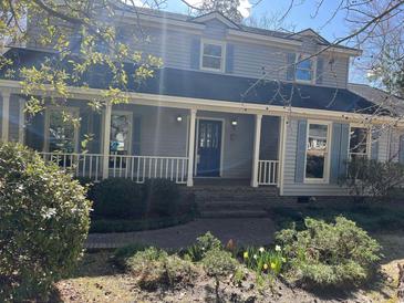 Charming two-story home featuring a welcoming porch, blue shutters, and beautiful landscaping at 5704 Woodside Ave., Myrtle Beach, SC 29577