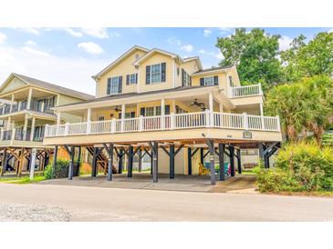 Inviting two-story beach house with a wide porch, an upper deck, black shutters, and a spacious ground-level parking area at 6001 - Mh69B South Kings Hwy., Myrtle Beach, SC 29575