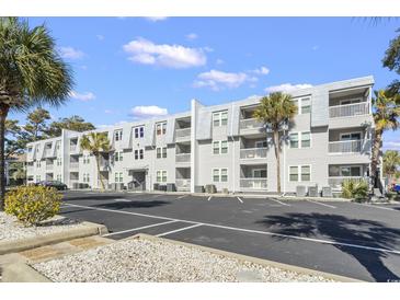 Three-story condo building featuring grey siding, white trim, balconies, and mature landscaping, with ample parking at 401 Hillside Dr. N # 2F, North Myrtle Beach, SC 29582