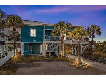 Inviting coastal home featuring a turquoise exterior, white railings, and lush palm trees in the landscaped front yard at 409 25Th Ave. N, North Myrtle Beach, SC 29582