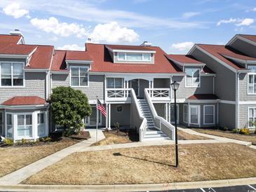 Attractive townhome featuring a two-story entrance, grey shake siding, and a vibrant red roof for eye-catching curb appeal at 4396 Baldwin Ave. # 138, Little River, SC 29566