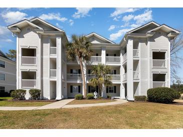 Beautiful white condo building featuring multiple stories and balconies with tropical landscaping at 597 Blue River Ct. # H2, Myrtle Beach, SC 29579