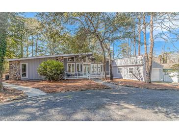 Inviting home featuring stone accents, a covered porch, and a well-maintained gravel driveway surrounded by mature trees at 67 Massick Ln., Pawleys Island, SC 29585