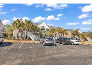 Condominium exterior showcasing tropical landscaping, and ample parking at 881 Palmetto Trail # 103, Myrtle Beach, SC 29577