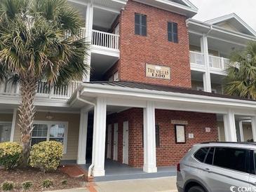 A sunny view of this condo building showcasing lovely architectural detail, palm trees and brick at 1101 Louise Costin Ln. # 1308, Murrells Inlet, SC 29576